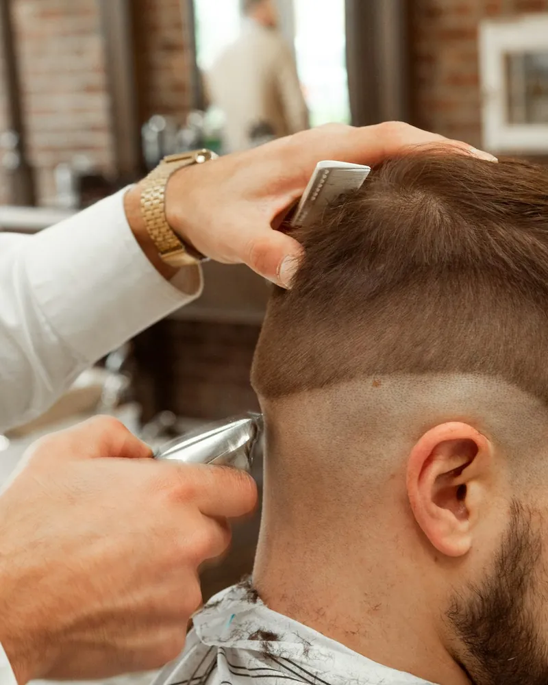 High skin fade being cleaned up with clippers, side view