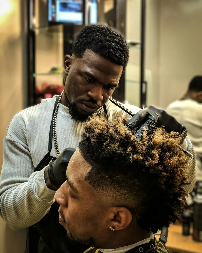 Barber in gloves shaping a curly top with a faded side