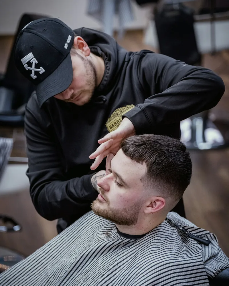 Barber in a cap checking a fresh low fade on a client
